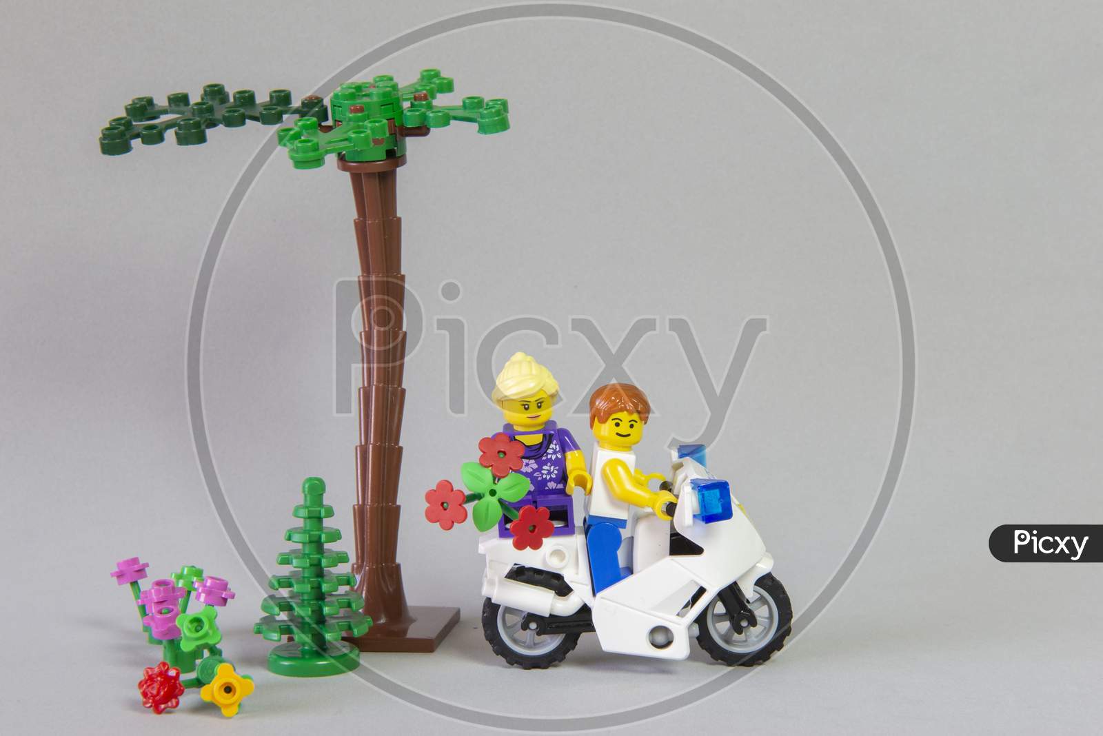 Florianopolis, Brazil. September 19, 2020: Minifigure Of Man Riding A Motorcycle With His Girlfriend On The Rump Holding A Bouquet Of Flowers On White Background. Valentine'S Day. Selective Focus.
