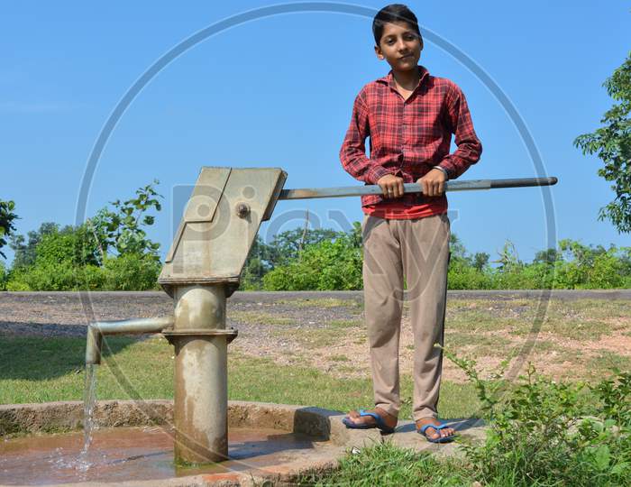 TIKAMGARH, MADHYA PRADESH, INDIA - SEPTEMBER 15, 2020: Unidentified indian village boy pumping hand water pump.