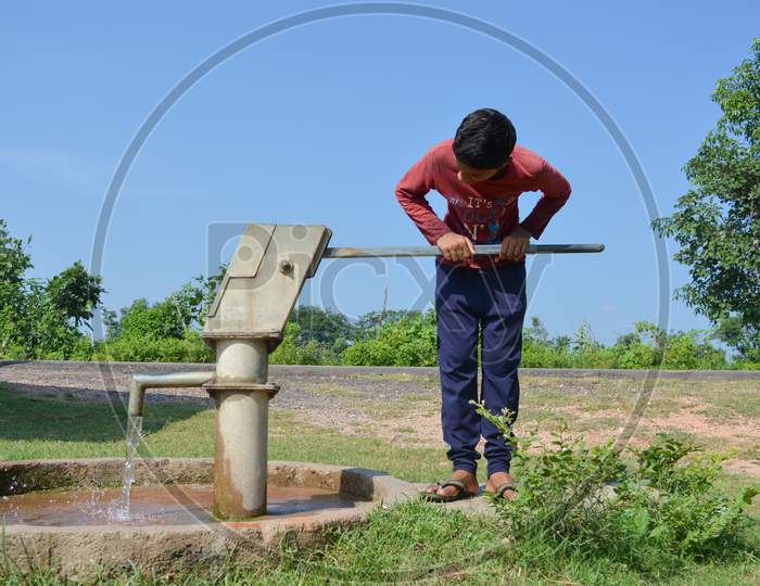 TIKAMGARH, MADHYA PRADESH, INDIA - SEPTEMBER 15, 2020: Unidentified indian village boy pumping hand water pump.