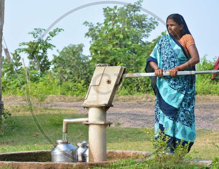 TIKAMGARH, MADHYA PRADESH, INDIA - SEPTEMBER 14, 2020: Unidentified Indian woman using hand pump for drinking water.