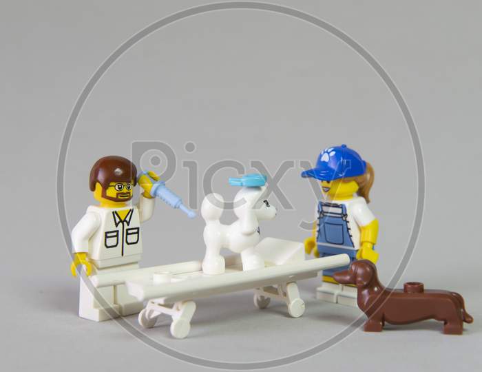 Florianopolis, Brazil. September 19, 2020: Vet Minifigure Giving Injection To A Sick Poodle Dog While Its Owner And Another Dog Observe Medical Care. Selective Focus. Dachshund.