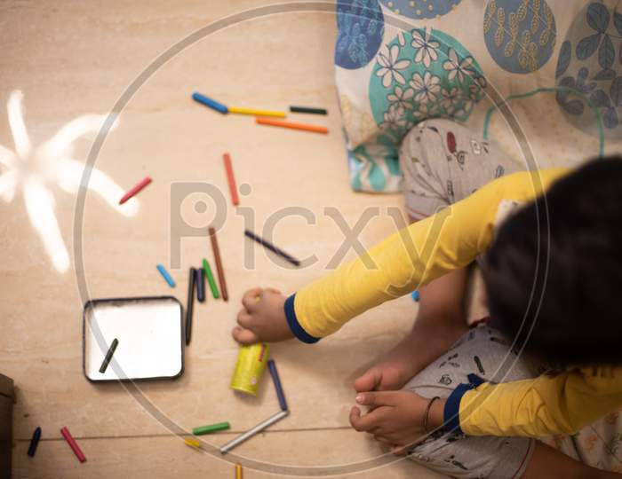 Top view picture of a baby boy playing with color pencils and crayons