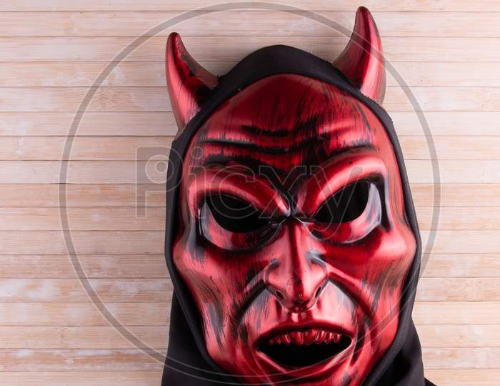 Red Devil Mask On Wooden Background With Copy Space.