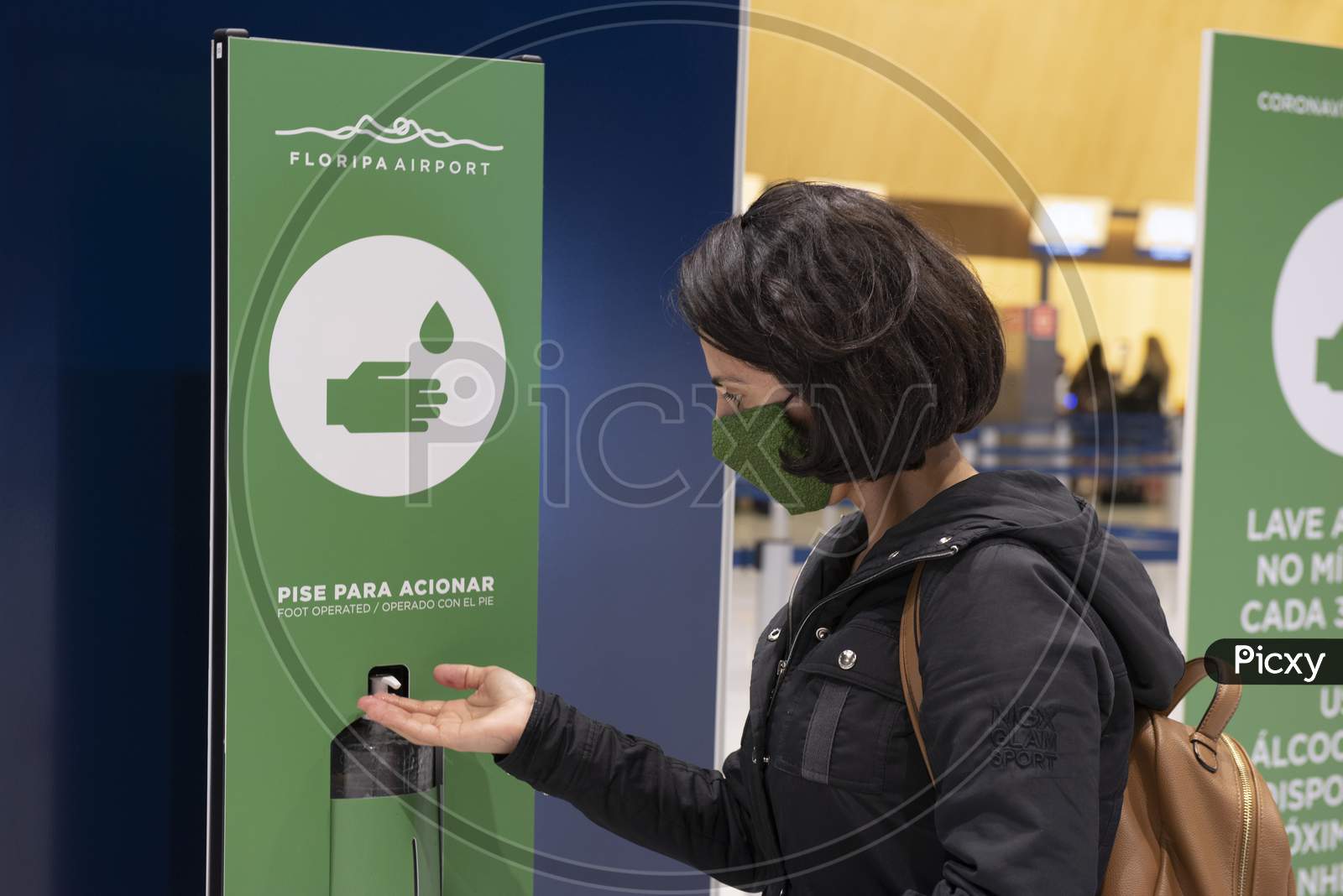 Florianopolis, Brazil. 15/09/2020: Young Woman Wearing Corona Contagion Mask Sterilizing Her Hands With Alcohol Gel In The Airport Lounge. Alcohol Gel Dispenser Distributed To Passengers.
