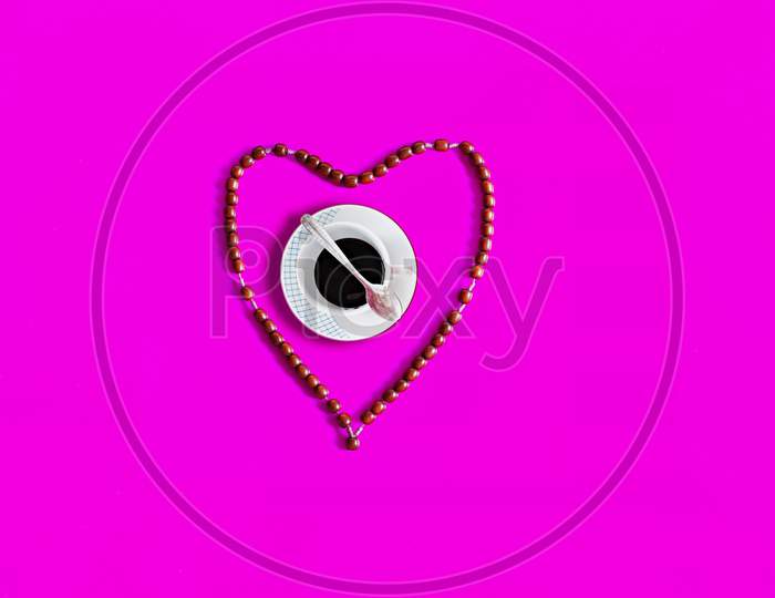 Coffee Mug Inside Rosary Love Shaped On Pink Background On International Coffee Day