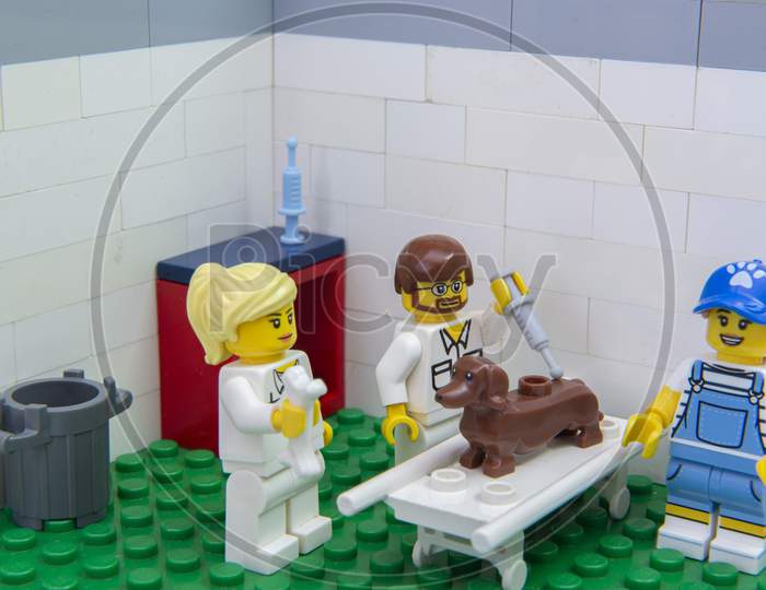 Florianopolis, Brazil. September 19, 2020: Vet Minifigure Giving Injection To A Dachshund Dog While A Nurse Distracts Him With A Bone At Clinic. Concept Of Care For Pets. Selective Focus.
