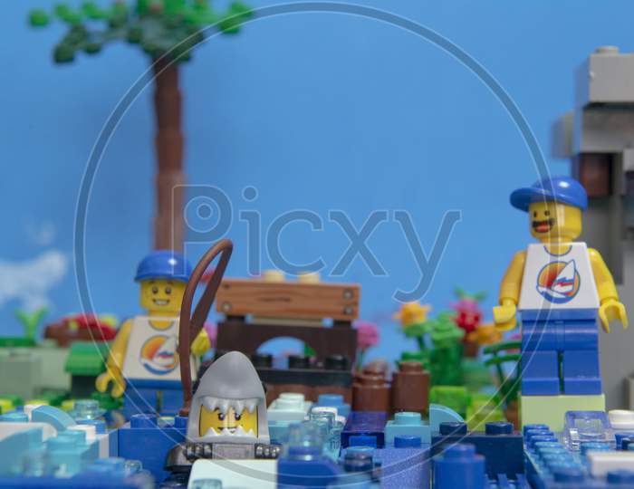 Florianopolis, Brazil. September 20, 2020: Happy Man Minifigure Watching His Son Catch A Shark With A Fishing Rod. Funny Scene. Family Leisure Concept. Selective Focus.