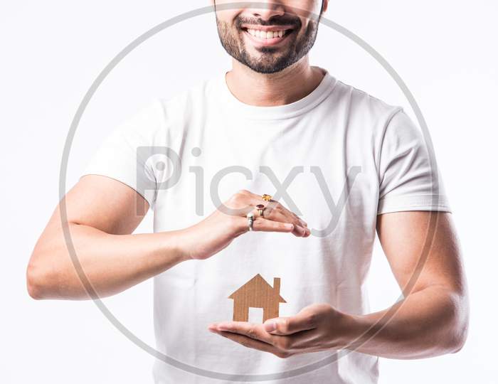 Real Estate Concept - Indian Handsome Man Holding Cut Out Of Paper House Model