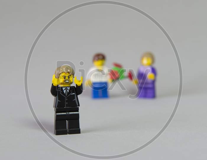 Florianopolis, Brazil. September 19, 2020: Minifigure Of Angry And Jealous Girl For Her Friend Receiving A Bouquet Of Flowers From A Boy On White Background. Selective Focus. Copy Space.