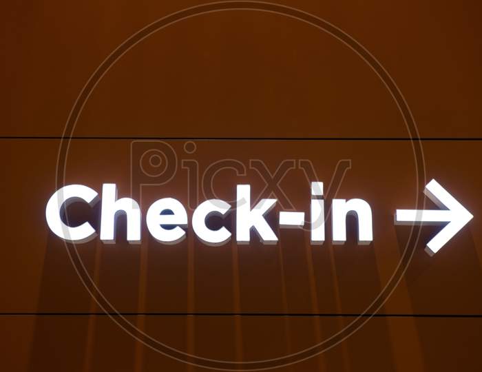 Airport Check-In Illuminated Sign With A Arrow Pointing To Right In A Wall.
