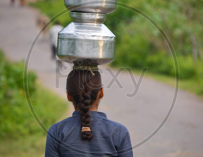 Unidentified Indian girl carry water on their heads in traditional pots from well, everyday Women walk few kilometers to get it due to drought.