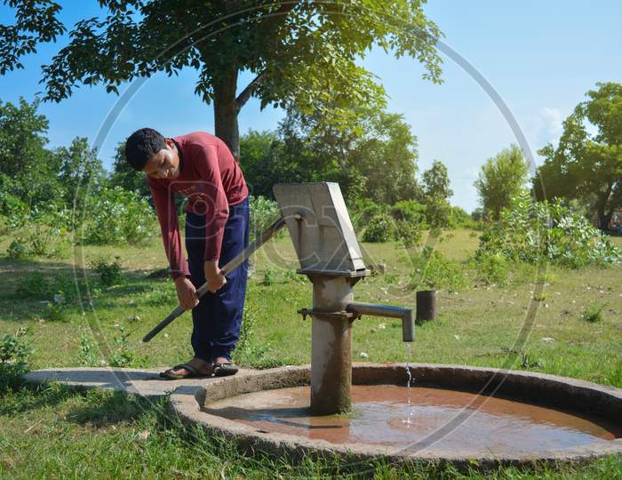 TIKAMGARH, MADHYA PRADESH, INDIA - SEPTEMBER 15, 2020: Unidentified indian village boy pumping hand water pump.
