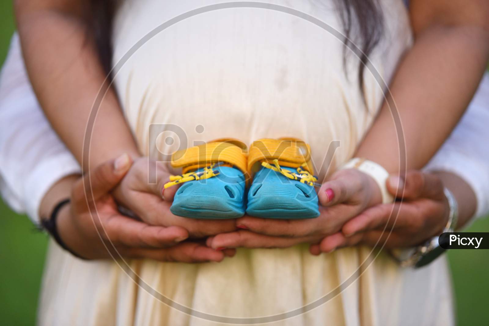 Newborn Baby Booties In Parents Hands, Pregnant Woman Belly. Maternity Concept .