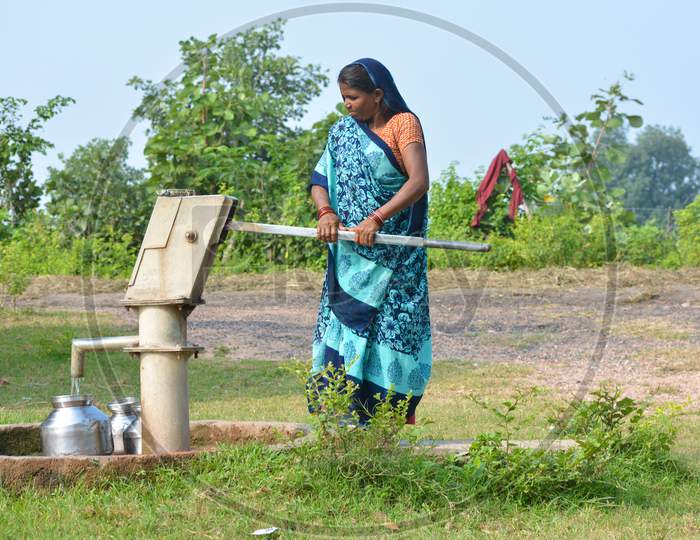 TIKAMGARH, MADHYA PRADESH, INDIA - SEPTEMBER 14, 2020: Unidentified Indian woman using hand pump for drinking water.