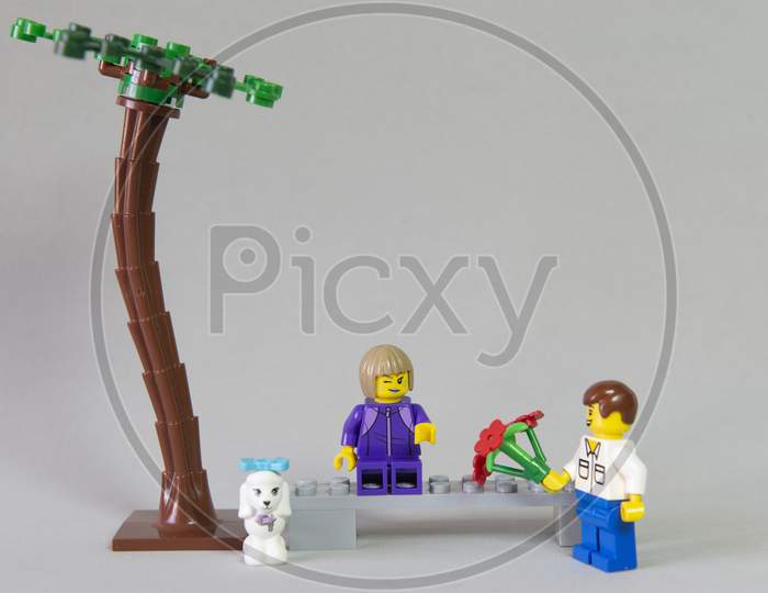 Florianopolis, Brazil. September 19, 2020: Minifigure Of Boy Giving A Bouquet Of Flowers To His Girlfriend In A Forest Garden On White Background. Valentine'S Day. Selective Focus. Copy Space.