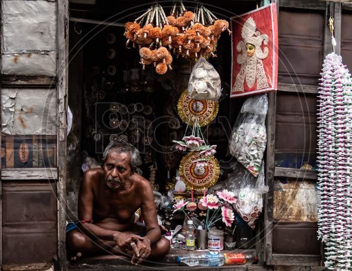 Old Man At His Shop Selling Puja Related Things.