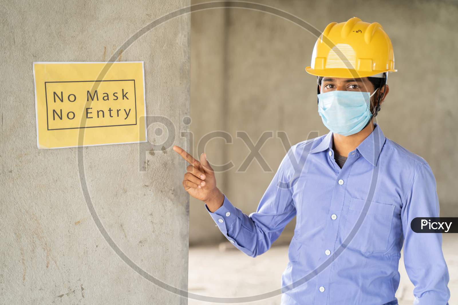 Worker Pointing No Mask No Entry Signage Notice Board On Wall At Working Construction Site To Protect From Coronavirus Or Covid-19 At Workplaces - Concept Of Health And Labor Safety During Pandemic