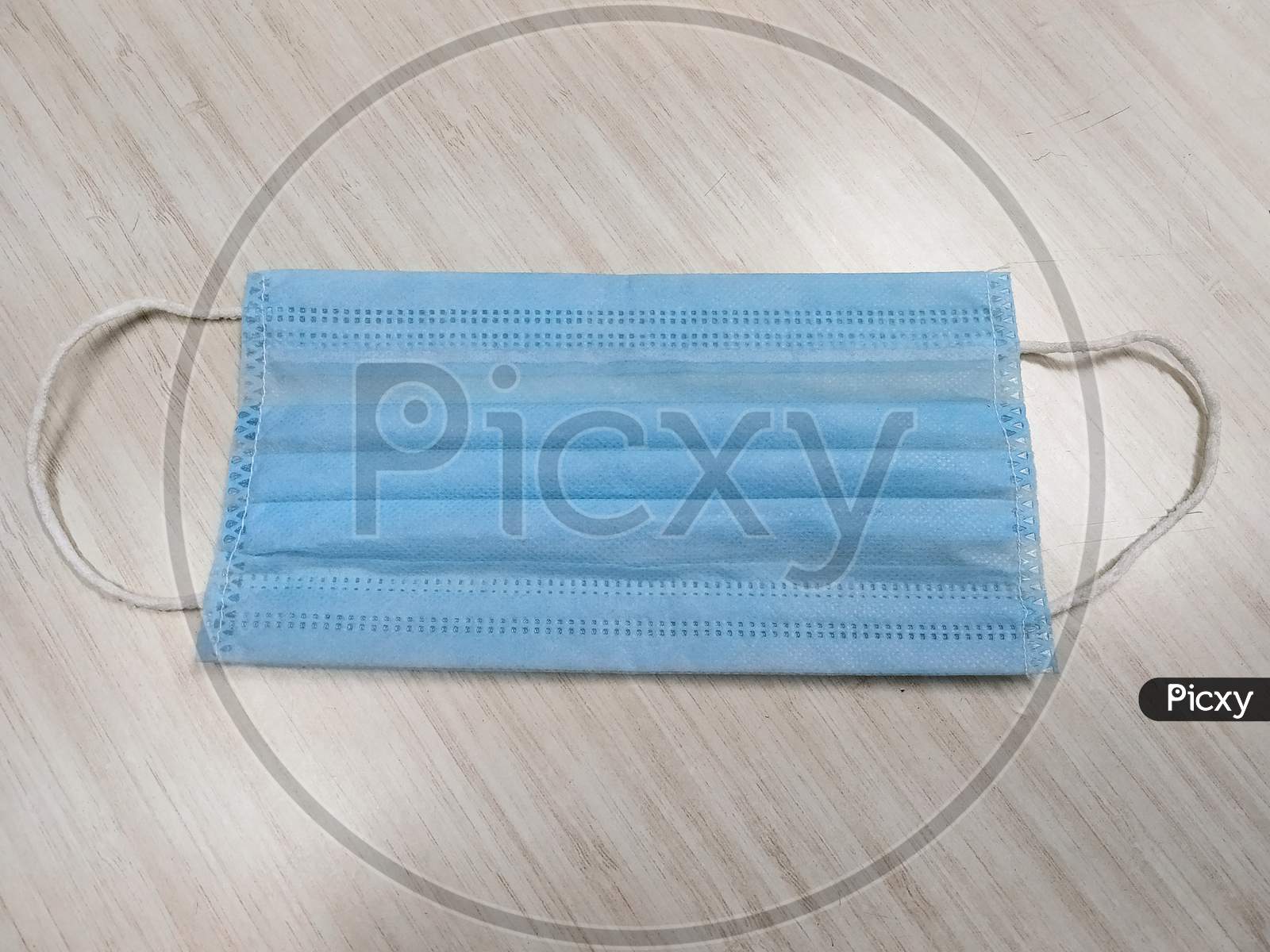 A 3 Ply Surgical Mask In A Wooden White Background