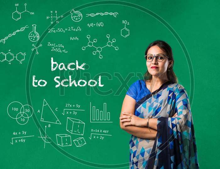 Portrait Of Asian Indian Lady Teacher In Saree Stands Against Writing Board Conducting Online Class