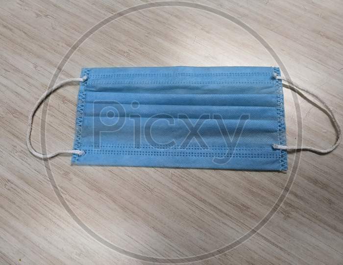 A 3 Ply Surgical Mask In A Wooden White Background