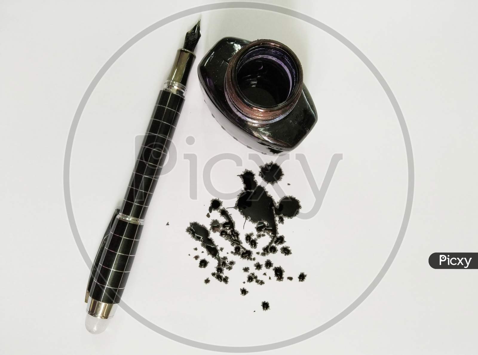 A Ink Pen With Black Ink Scattered On Paper And A Ink Bottle