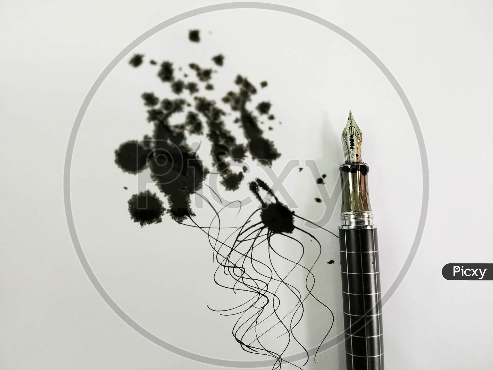 A Ink Pen With Black Ink Spread On Paper