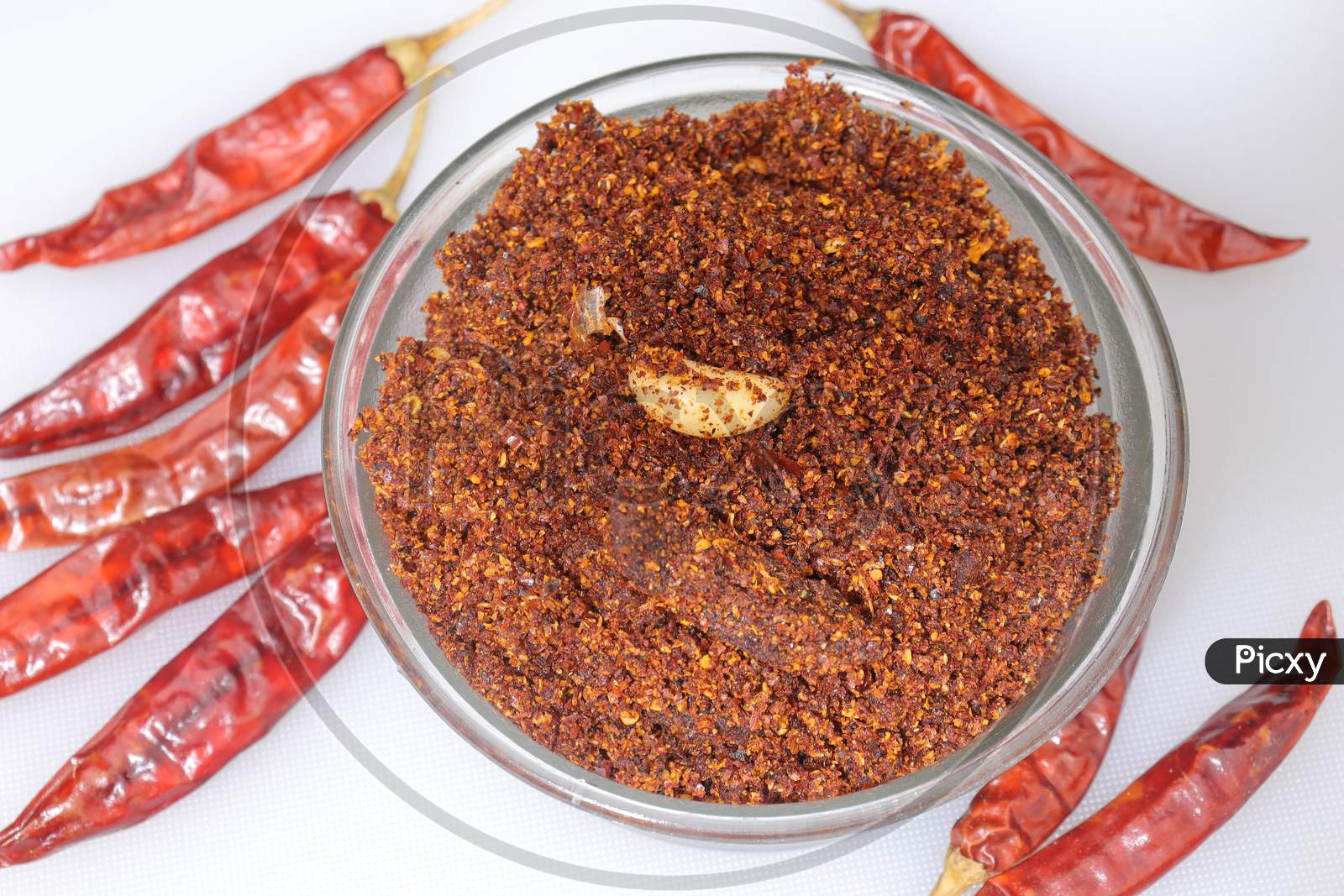 Dry hot red chillies powder on white background from top view.