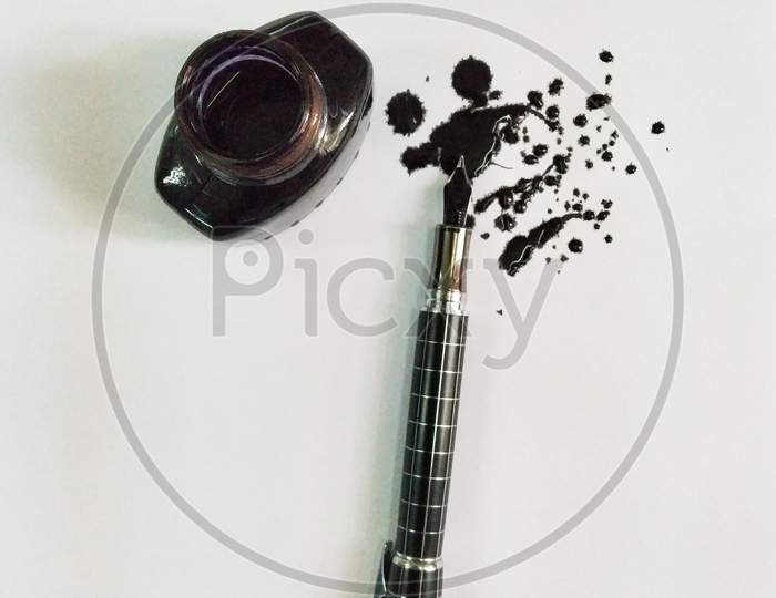 A Ink Pen With Black Ink Scattered On Paper And A Ink Bottle