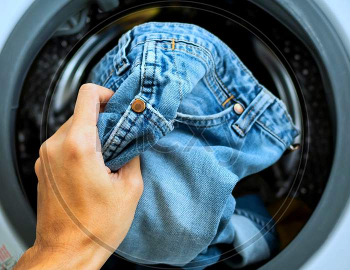 Putting Jeans Into The Washing Machine