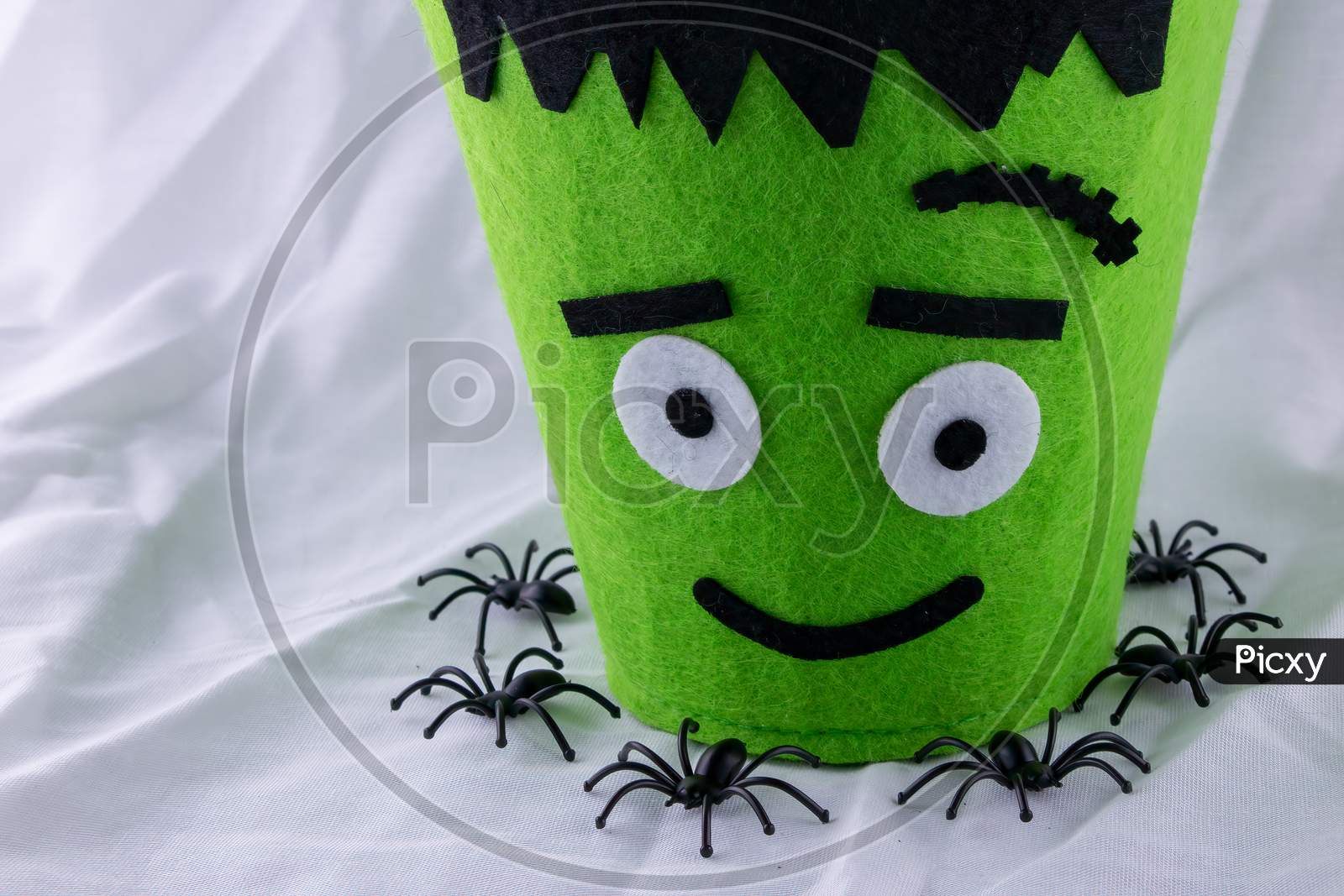 Halloween Fun For Kids Going Out To Trick Or Treat. Green Monster Candy Bags In A Nest Of Black Plastic Spiders