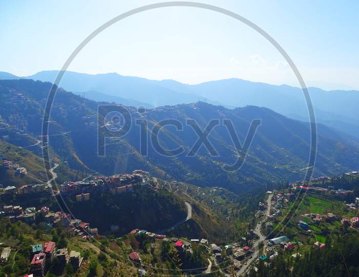 Landscape view of beautiful city Shimla situated in himachal pradesh in the mountain range of great himalayas at sunrise time with houses, trees and birds