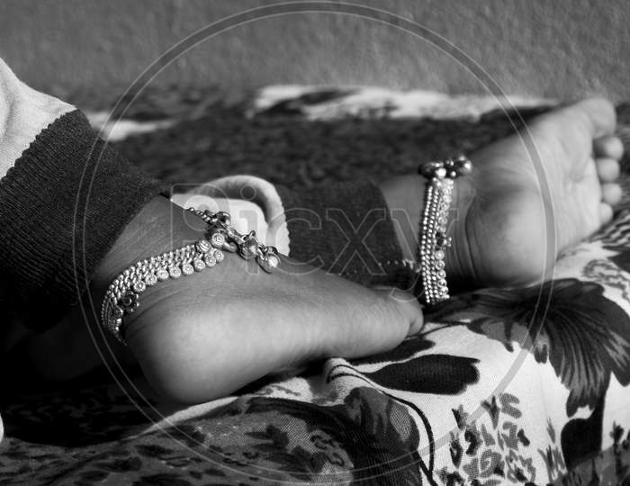 Closeup Of Indian Girl Child Decorated Ankle Silver Chain Isolated On Barefoot In Black & White Photo