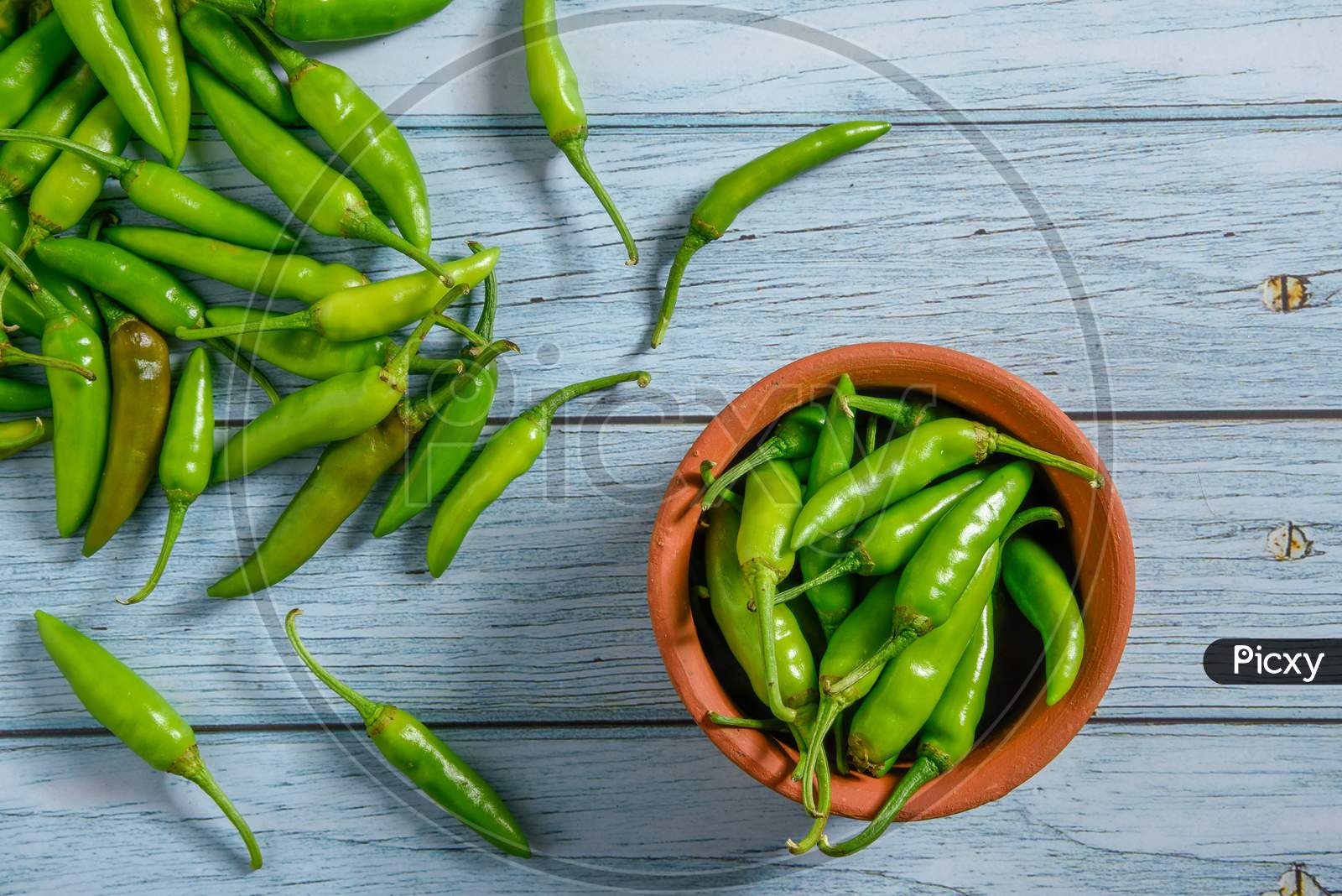 Green Chilly On Wooden Background.Fresh And Raw Green Chili Isolated