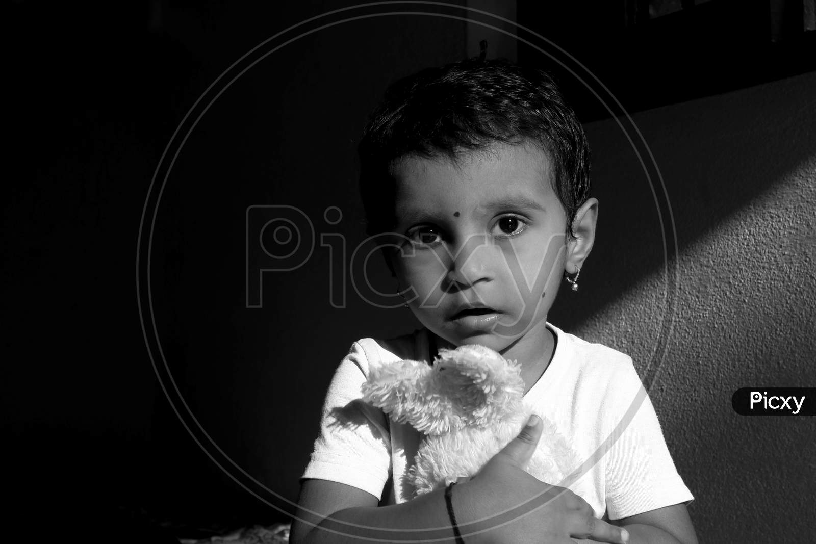 Closeup Shot Of Indian Girl Child Holding Doll In Morning Sunlight Monochrome Stock Photo