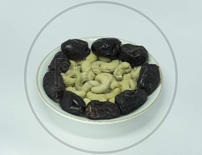 Image Of Healthy Dates And Cashew Nuts On White Ceramic Plate.