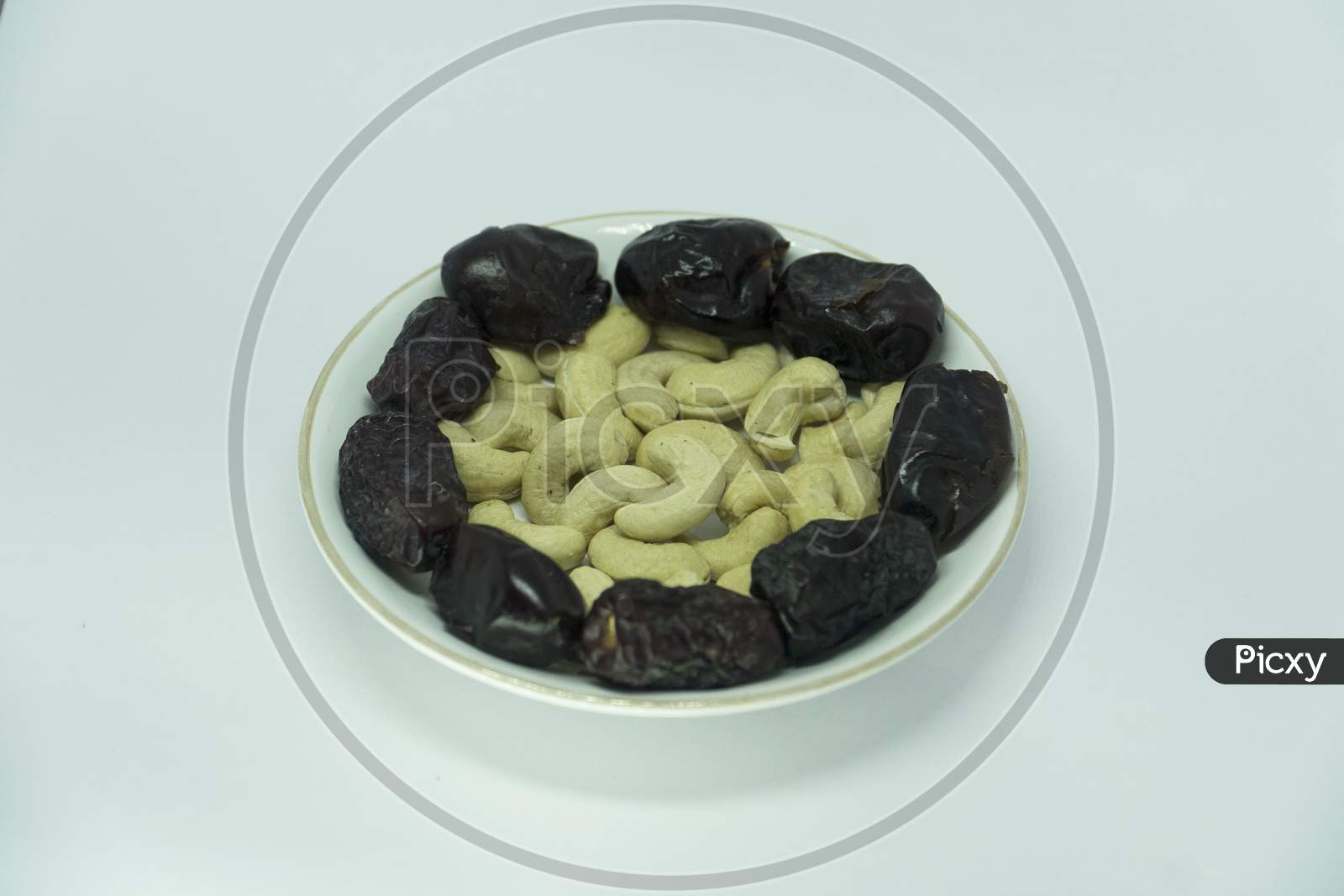 Image Of Healthy Dates And Cashew Nuts On White Ceramic Plate.