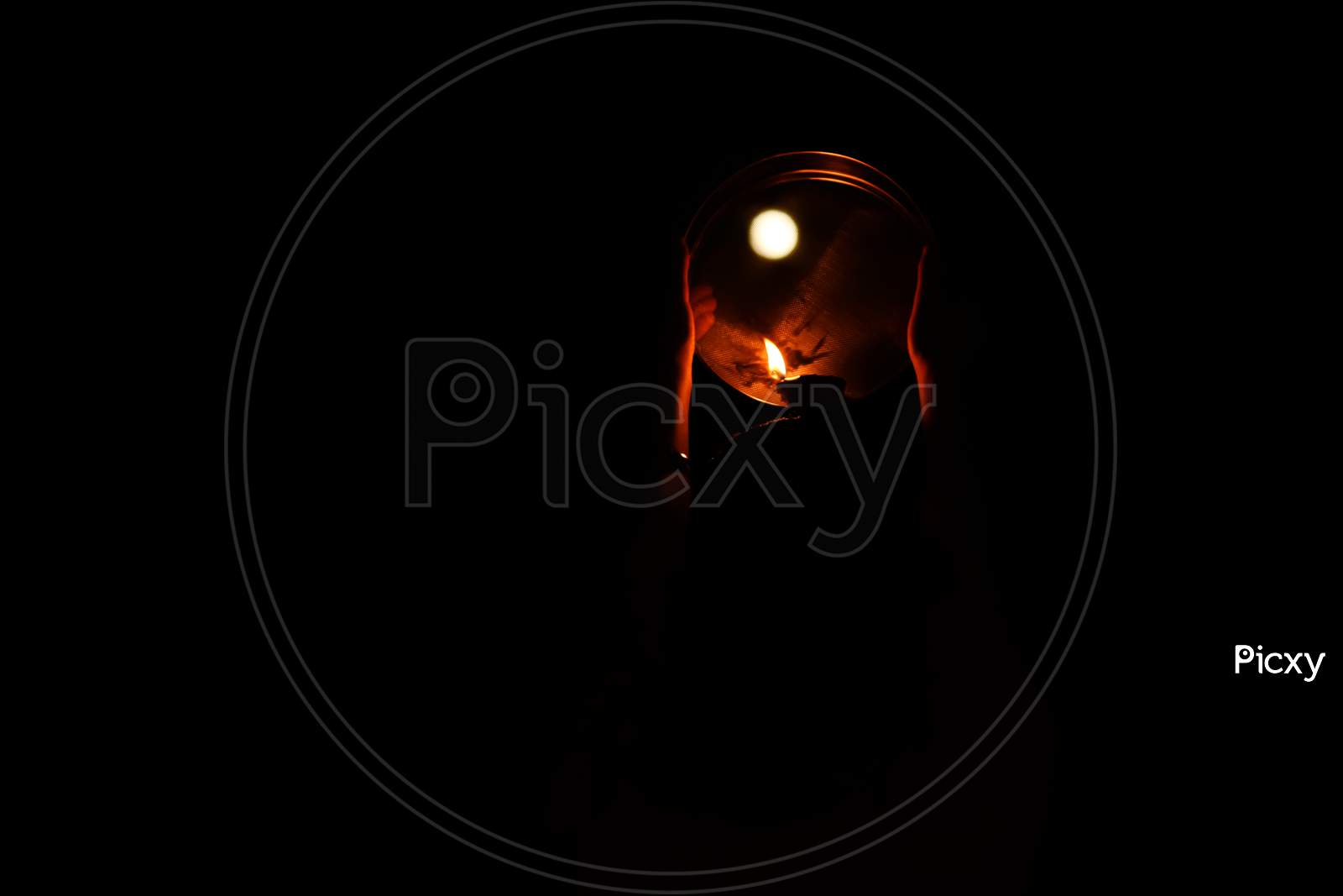 Karwa Chauth pooja burning candle against the moon on black background