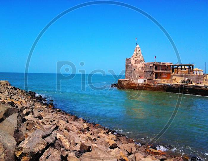 Beautiful view of arabian sea near Dwarka Temple of hindu god Lord Krishna where river Gomti meet with sea and big stones on bank of sea.