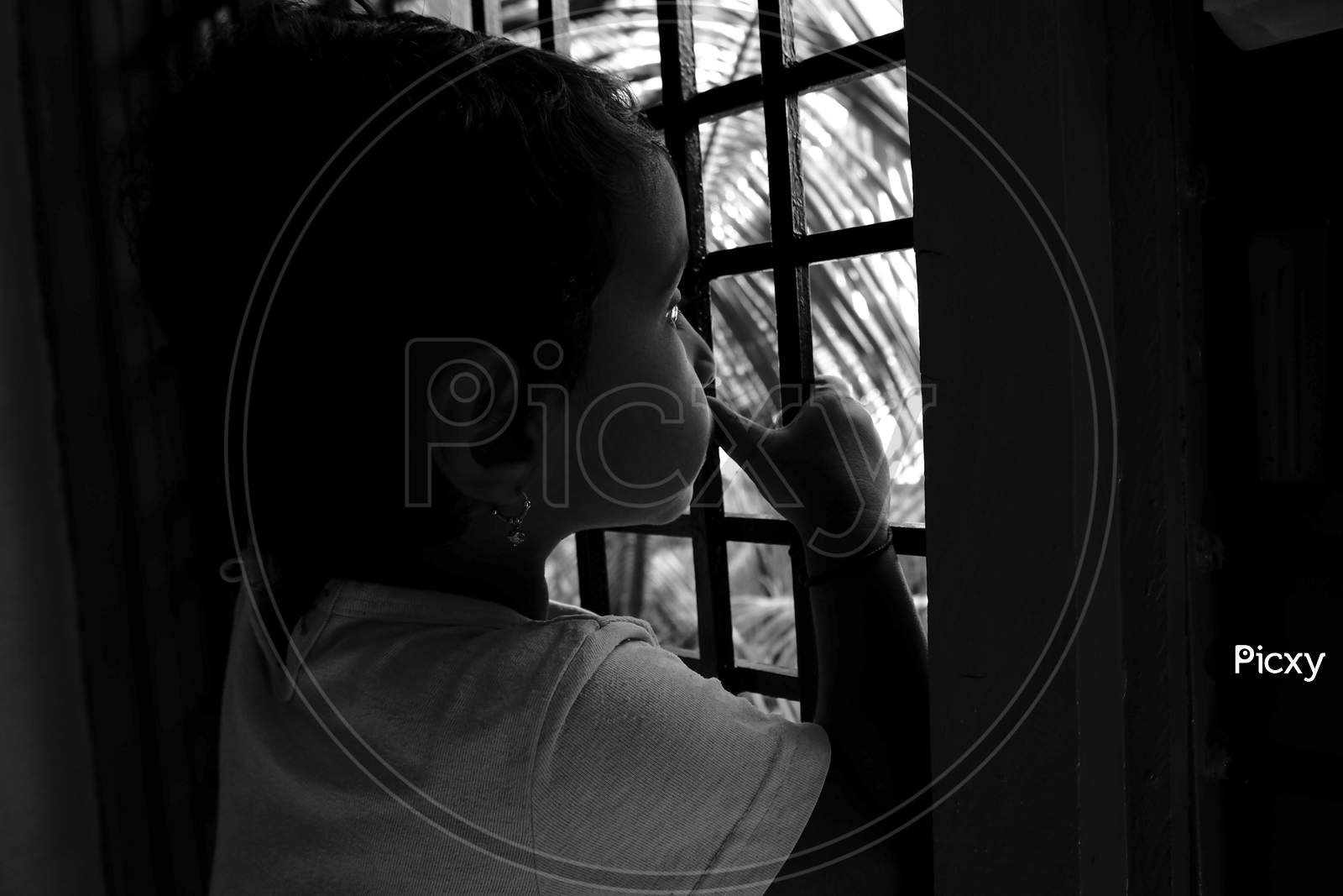 Close Shot Of Indian Girl Child Peeping In Window Outside The Nature In Monochrome Photo