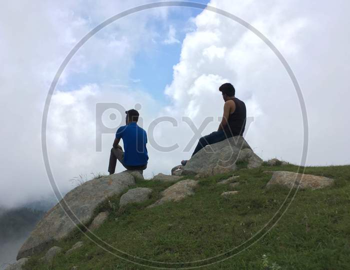 Two boys are sitting on the top of the mountain