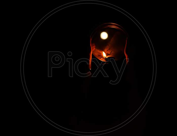 Karwa Chauth pooja burning candle against the moon on black background