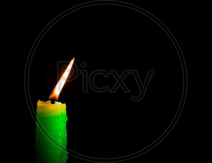 One burning green candle isolated on dark background
