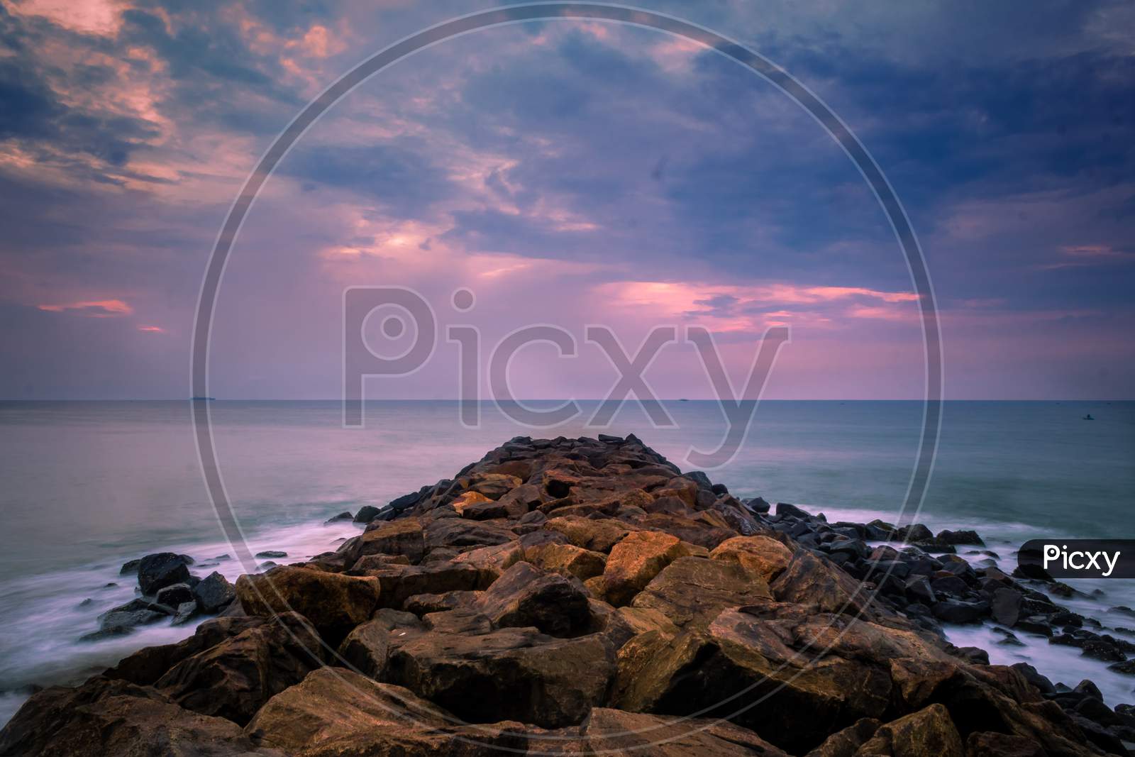 Beautiful Sunrise Over The Beach In Long Exposure. Moving Elements Sunrise And Wave Photography From The Rocky Beach In India. Wave Breaker Rocks, Slow-Shutter Sea Waves And Rocks Photography.