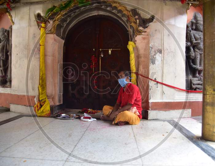 A priest sits the inside the premises of Kamakhya Temple, as it re-opens for public after a gap of nearly six months due to coronavirus lockdown with certain restrictions, in Guwahati, on October 11, 2020