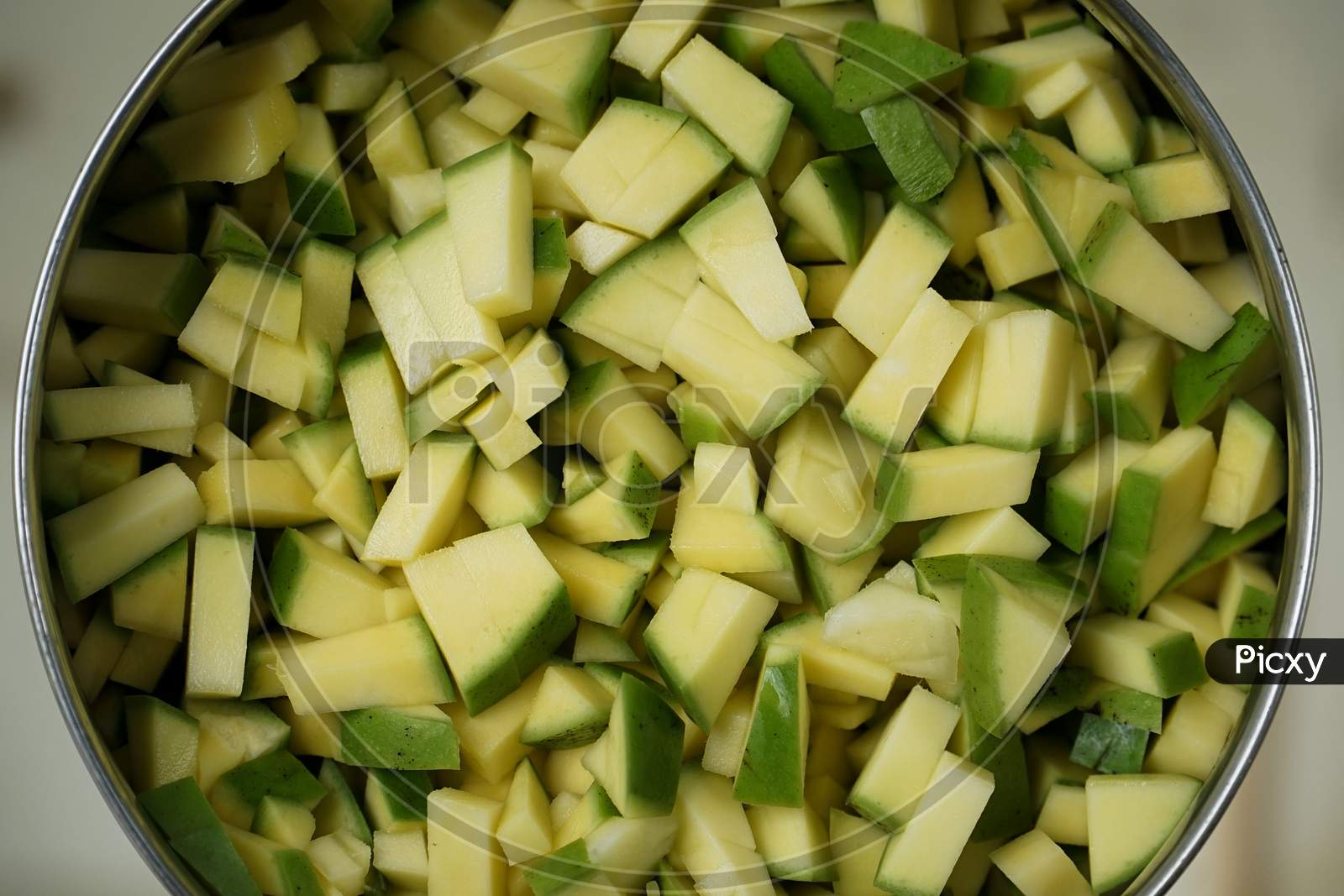 Close Up Image Of Fresh Chopped Green Mango Pieces For Cooking In A Stainless Steel Bowl.