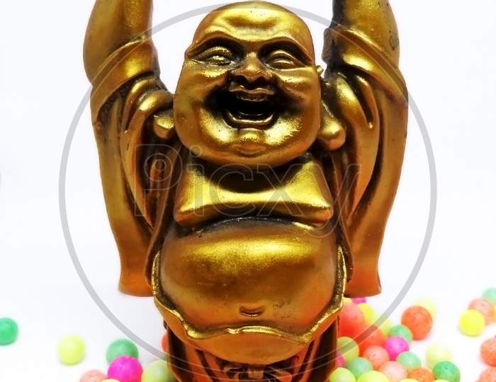 Laughing Buddha statue with colorful small polystyrene balls on white background