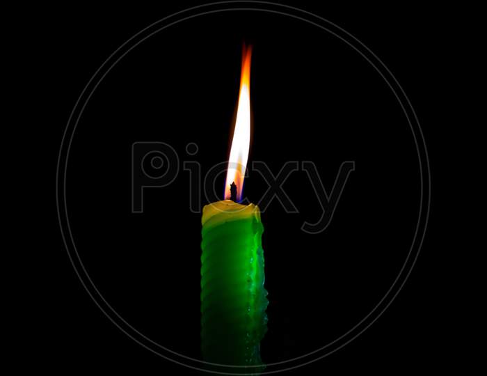 Burning green candle on dark background
