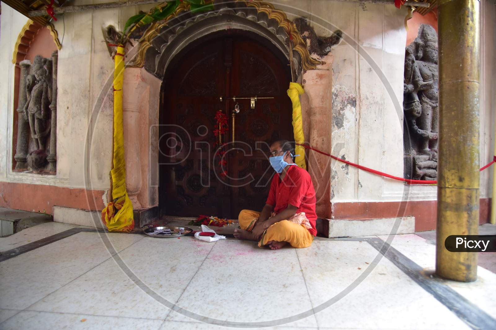 A priest sits the inside the premises of Kamakhya Temple, as it re-opens for public after a gap of nearly six months due to coronavirus lockdown with certain restrictions, in Guwahati, on October 11, 2020