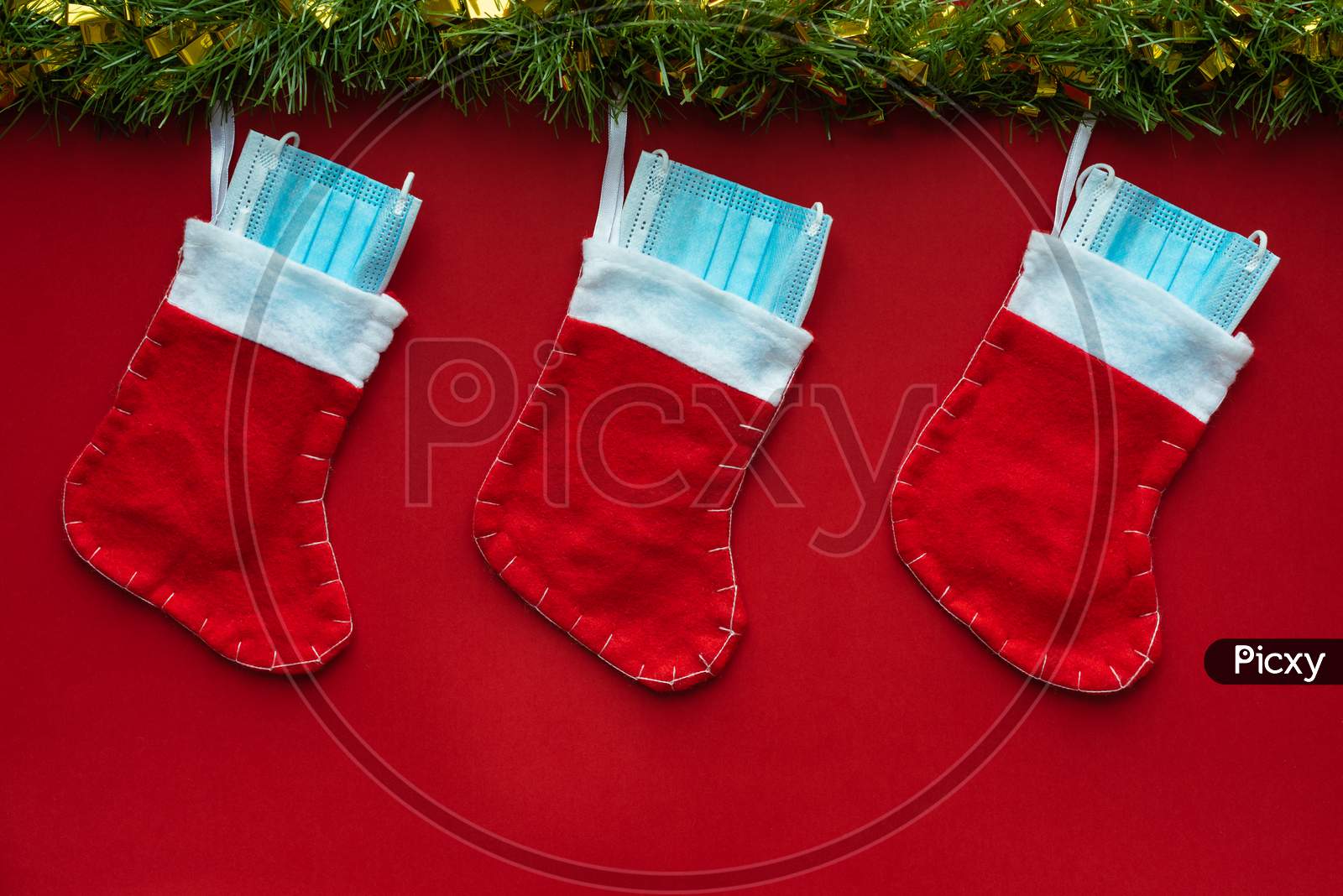 Christmas Decoration With Coronavirus On A Red Background, Christmas Socks, Face Masks And Hydroalcoholic Gels. Covid Concept On Christmas.