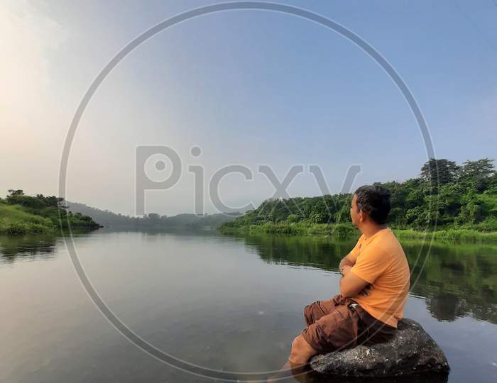 Man sitting on rock watching river